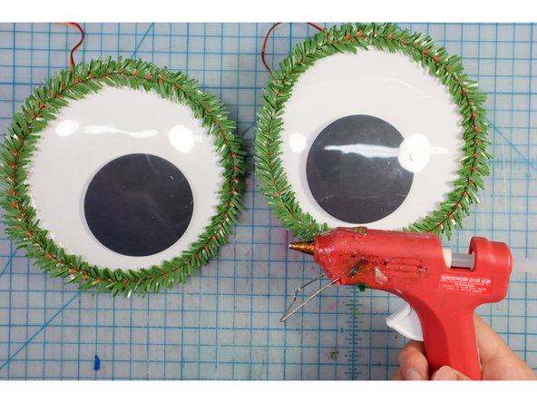 Glue evergreen pipe cleaners around the eyes as shown.