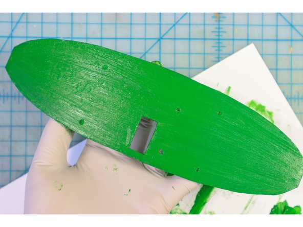 Paint the backplate green to make it blend into the green branches.