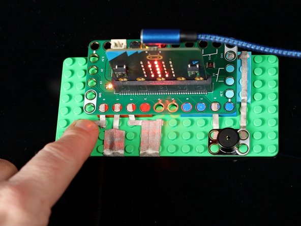 Touching the tape connected to Pin 0, 1, or 2 will play a tone on the Piezo Speaker and also show a number on the micro:bit's built-in LED matrix.