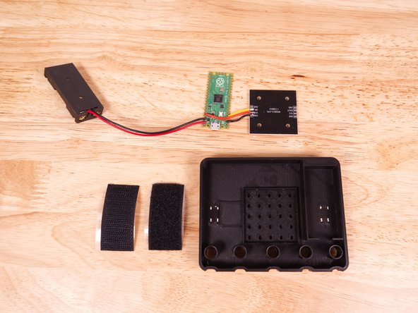 We're ready to start getting our electronics in place. We'll start by adding some hook &amp; loop, placing it over two of the legs of the B button. (Which is on the left side when the Micro:Bit is face down.)