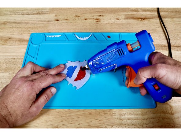 Squeeze a bead of hot glue around the outside perimeter of the mouth shape as shown in photo one.