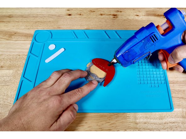 Using a hot glue gun and photo one for reference, squeeze a bead of hot glue across the lowest edge of the hat.