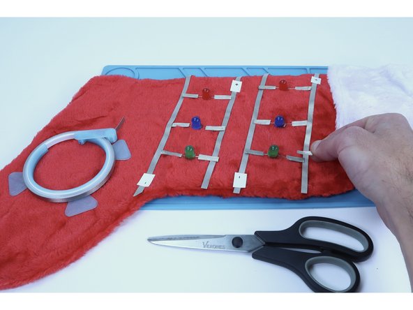 Now, snip and place small pieces (again, 12 in total for our project) of Maker Tape to connect the legs to their respective positive/negative long path.