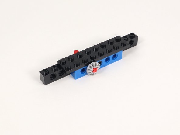 Insert the axle into the hole to the left of the hole with the black pin.