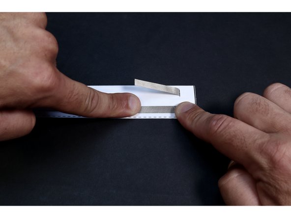 With the two sections of Maker Tape pressed in place on the non-marked side of this shape, flip it over and choose the section located on the side with the remaining marks to peel/cut the backing from. Stick it in place down the center of its' section  as shown. DO NOT stick the other section down yet.