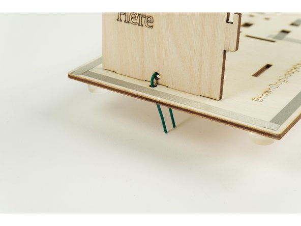 Take one of the short pieces of wire and bend it into a &quot;U&quot; shape as shown, then thread it through the hole in the bottom of one of the walls.