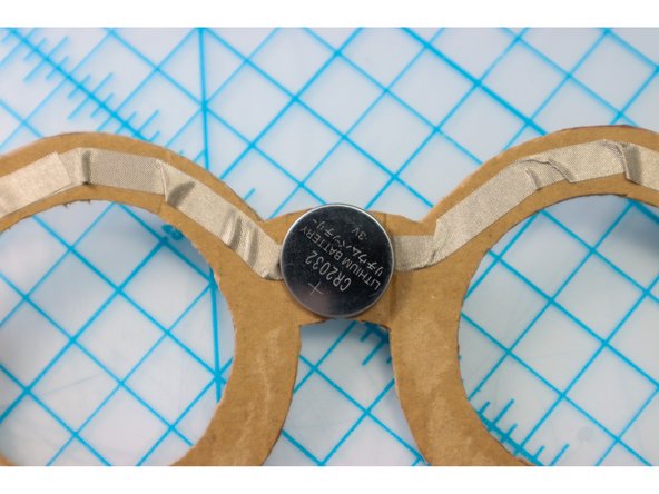 Place the battery on top of the piece of Maker Tape, making sure it is centered on the bridge of the frame.