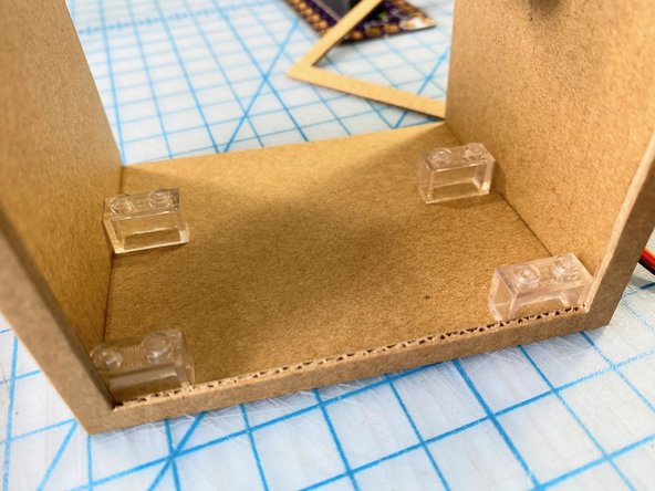 Because the Bit Board fits perfectly on LEGO, we used superglue to attach four LEGO pieces to the cardboard base so that we could add and remove the Bit Board as we built it.