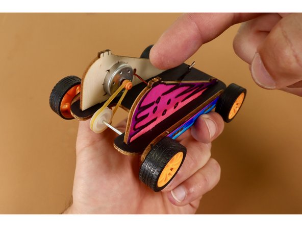 At this point, you will need to stretch and seat the rubber band on the grooves of both the orange motor axle/spindle wheel and the white axle wheel. If your white plastic wheel isn't lined up with the orange wheel, simply slide it into alignment.
