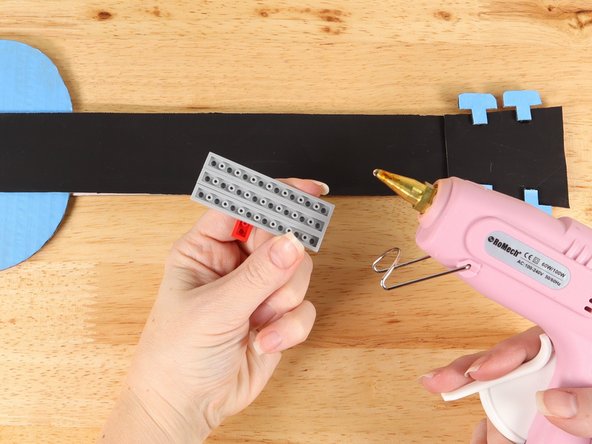 Using hot glue or another strong glue, attach the LEGO plates to the neck of the guitar.