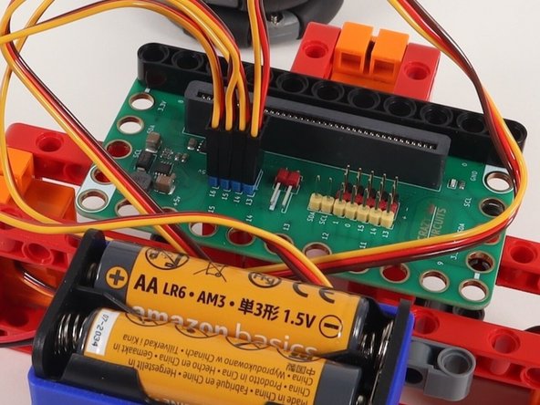 Plug the left servo connector into the row for Pin 13. The orange wire should go to the pin closest to the 13 on the board, the red wire goes into the +5v row, and the brown wire goes into the - row, which is ground.