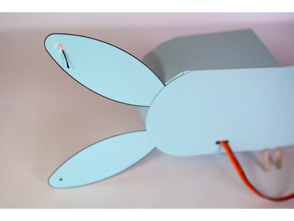 Add a drop of glue on the back of the ear so the knot doesn't pull through the paper