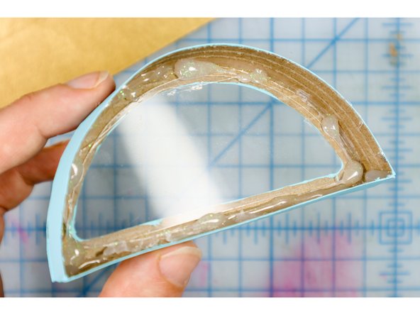 Use hot glue to secure the plastic inside the window of the box. A few dabs of glue will work, just be sure to keep the glue away from the edge so that you can't see it from the front.