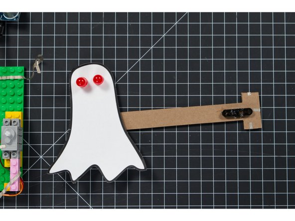 If you want to add LEDs for the eyes, use a safety pin to poke two holes for each eye so you can put the LED legs through the paper and the cardboard. Once you have the holes, put the LED legs through with the shorter leg (ground) on each LED towards the center.