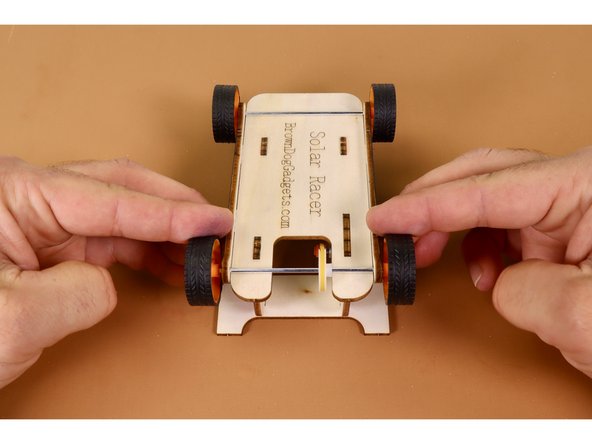 Find the larger of the two remaining body panels and lay it flat on the table with the open part of the &quot;U&quot; oriented toward you.  Holding the chassis with the engraved side up and the notched end of the chassis toward you, press the two downward-facing tabs nearest the motor into the two slots of the u-shaped rear spoiler.