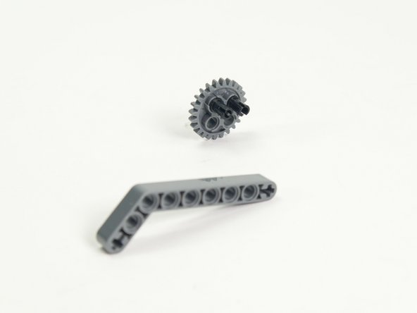 Build the arm as shown by inserting two black pins into the large gear, then attaching the angled beam.