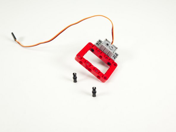 Add two short pins to the frame, opposite the servo.