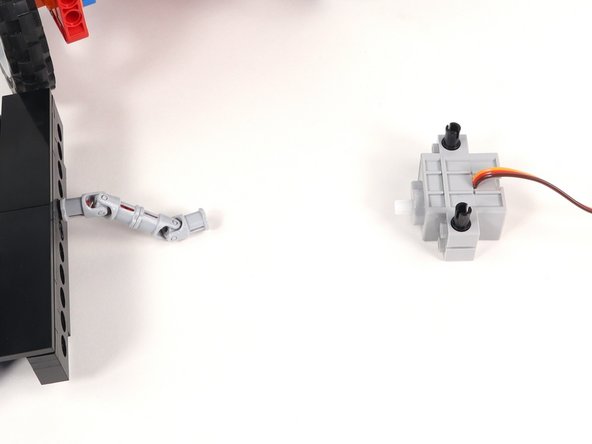 Connect the servo shaft to the universal joint on the Claw with the black pins and the wires facing down.