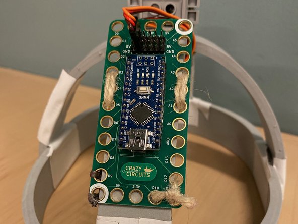 Thread the twine through the holes in the Crazy Circuits board and tie a knot as shown.