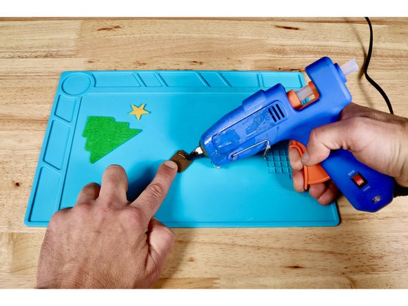 Using a hot glue gun and photo one for reference, squeeze a bead of hot glue onto the top edge of the tree trunk.