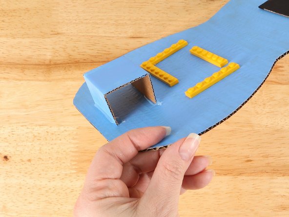 Glue the battery compartment into place below the LEGO plates. Make sure it is not too close to the LEGO plates.