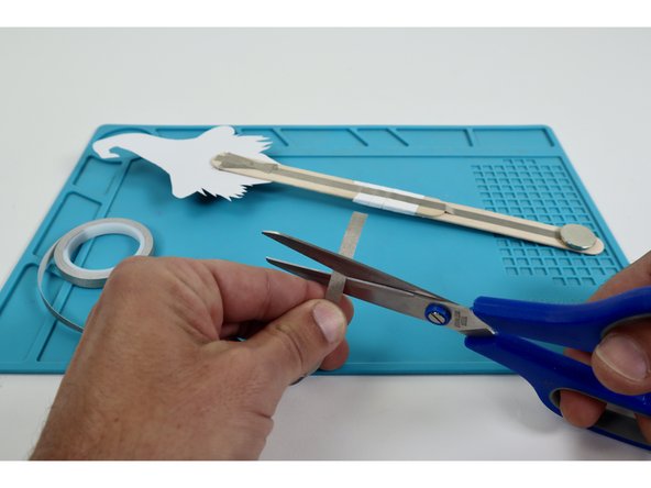 Finish installing the battery and turn the LEDs on.  To do this, measure, cut, peel, and stick a piece of Maker Tape that can reach from the top of the battery  around to the path on the opposite side of the wand handle.