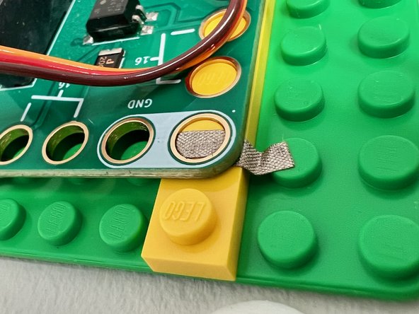 Place a small piece of Maker Tape on the bricks under the corners of the Bit Board to make it fit snugly on the pegs. If you don't have Maker Tape, you could also use a strip of masking tape.