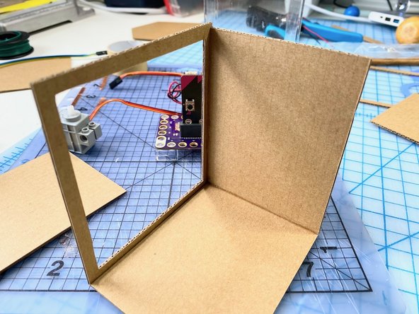 We cut out a frame of cardboard for the front of the body box, then created the side walls.