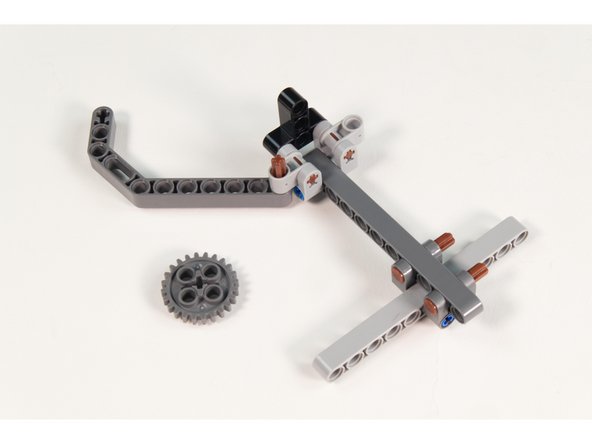 Press a LEGO Axle 4 with End Stop into the last hole on a LEGO Technic Beam 3 x 3.8 x 7 Beam Bent 45 Double as shown.