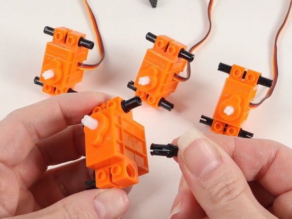 Add 4 black pins to a continuous rotation servo. You will need to do this to all 4 servos.