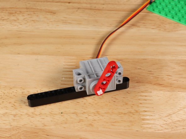 Attach a LEGO half beam with axle holes onto the shaft of the servo. The ghost will be taped onto this in a later step.