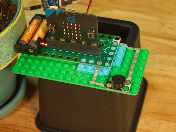 Now when the soil is too dry (based on the number you assigned to dryPlant you will see a sad face, and hear a beep. This will happen every 10 seconds (or whatever interval you set for the reminderTime variable.)