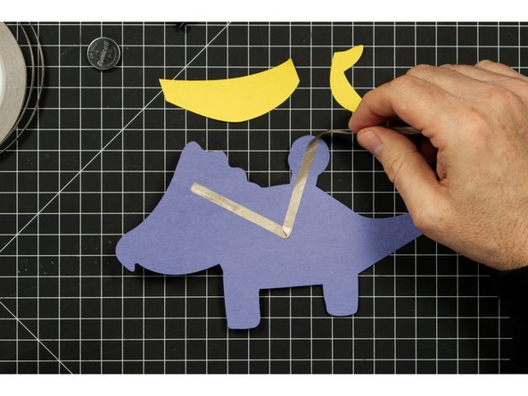 The tape should wrap around the round part to the front side of the Triceratops.