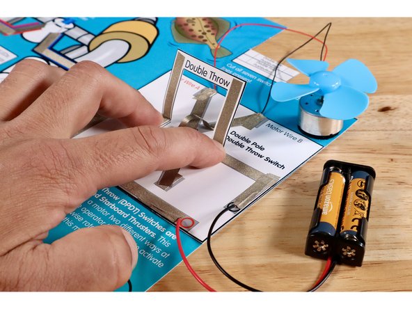 Press the folded squares of the switch lever to the Maker Tape loops you just stuck to the ends of the voltage paths. One side of the lever is now in contact with the rest of the circuit.