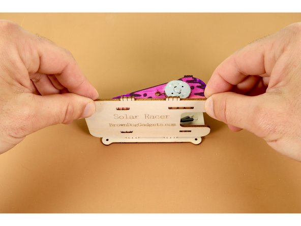 Now, grab one of the two matching long body panels that feature small holes at opposite ends and lay it flat against the table with the rounded drop-down ends facing you.