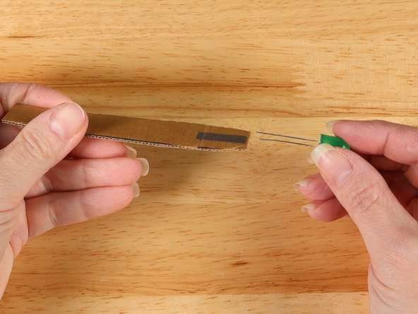 Slide an LED onto the handle so the cardboard goes in between the two LED legs.