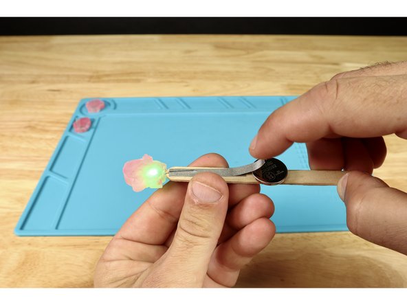 Cut one FINAL piece of Maker Tape and connect it to both the existing path from the longer positive LED leg AND the top of the battery. Your project should light-up when you do!