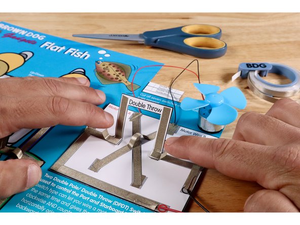 Cut, peel, and stick each of two small pieces of Maker Tape so half contacts the top of the square portion on the lever and the rest contacts the voltage path nearest to it. The opposite side of the lever is now in contact with the rest of the circuit.