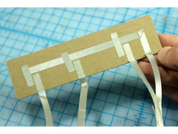 Add Maker Tape to the button base piece as shown. All switches are connected to ground (-), and the other pieces of Maker Tape will go to the pins.