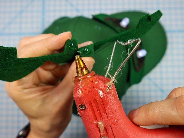 Glue the spikes to the hat starting at the hole in the back of the hat and continuing to the front.