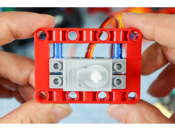 Add two blue pins to the front of the red frame as shown.