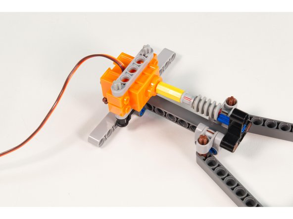 Slide the servo into place so one of the axles goes into the LEGO Technic Through Axle Connector with Bushing.