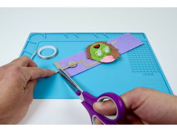 Measure, cut, peel, and stick a Maker Tape path that extends from the top of the battery to the edge pad nearest to it.