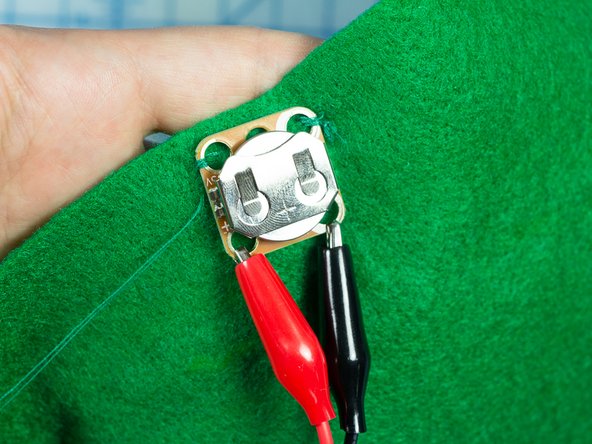 Using some green thread, sew the battery pack near the bottom of the tree so that you can easily remove the battery when it needs to be replaced.