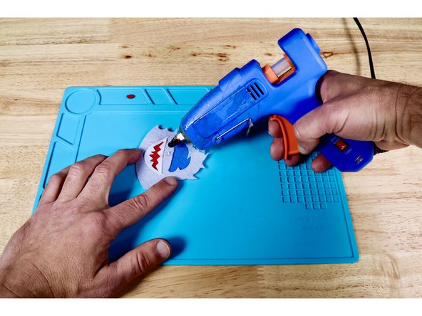 Squeeze a tiny dot of hot glue where the nose should go and press that piece into place as shown.