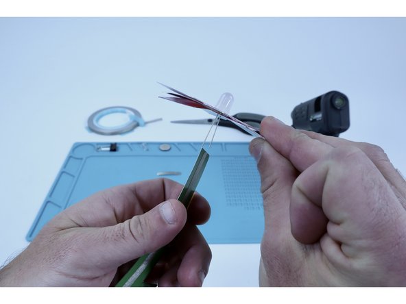 Peel one of your new tape segments and stick it on the corner of your work table. You'll have to briefly hold the flower in position with one hand in a moment and having the tape already peeled and ready to go will make the step after easier.