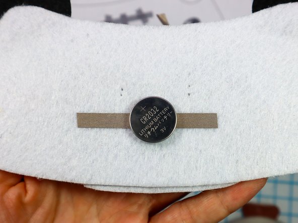 Make a loop of Maker Tape with the adhesive side out and place it on the negative side of the battery.