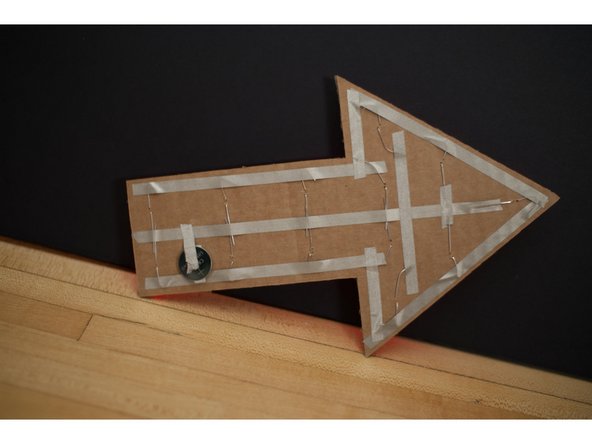 Use a short piece of tape to connect the center (positive) piece of tape to the top of the battery.