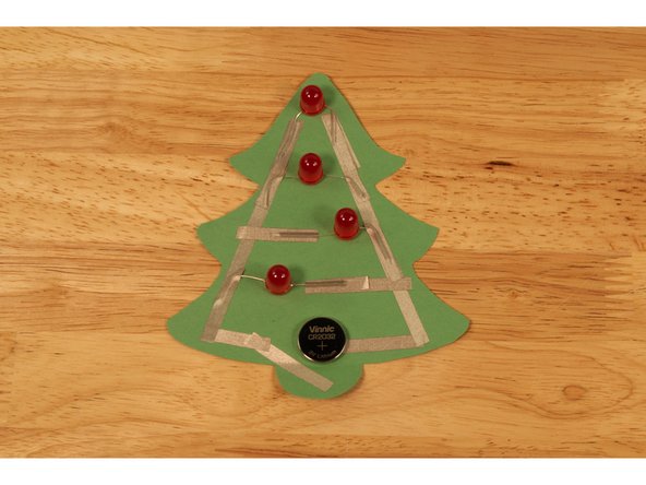 Fold over the tab at the bottom so the positive side tape (from the left side of the tree) is touching the top of the battery.