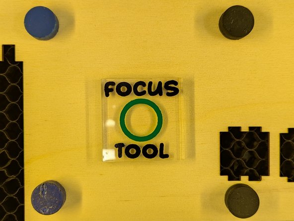 Grab the acrylic focus tool from the side of the laser cutter. Place it in the center of the area where you want to cut your project.